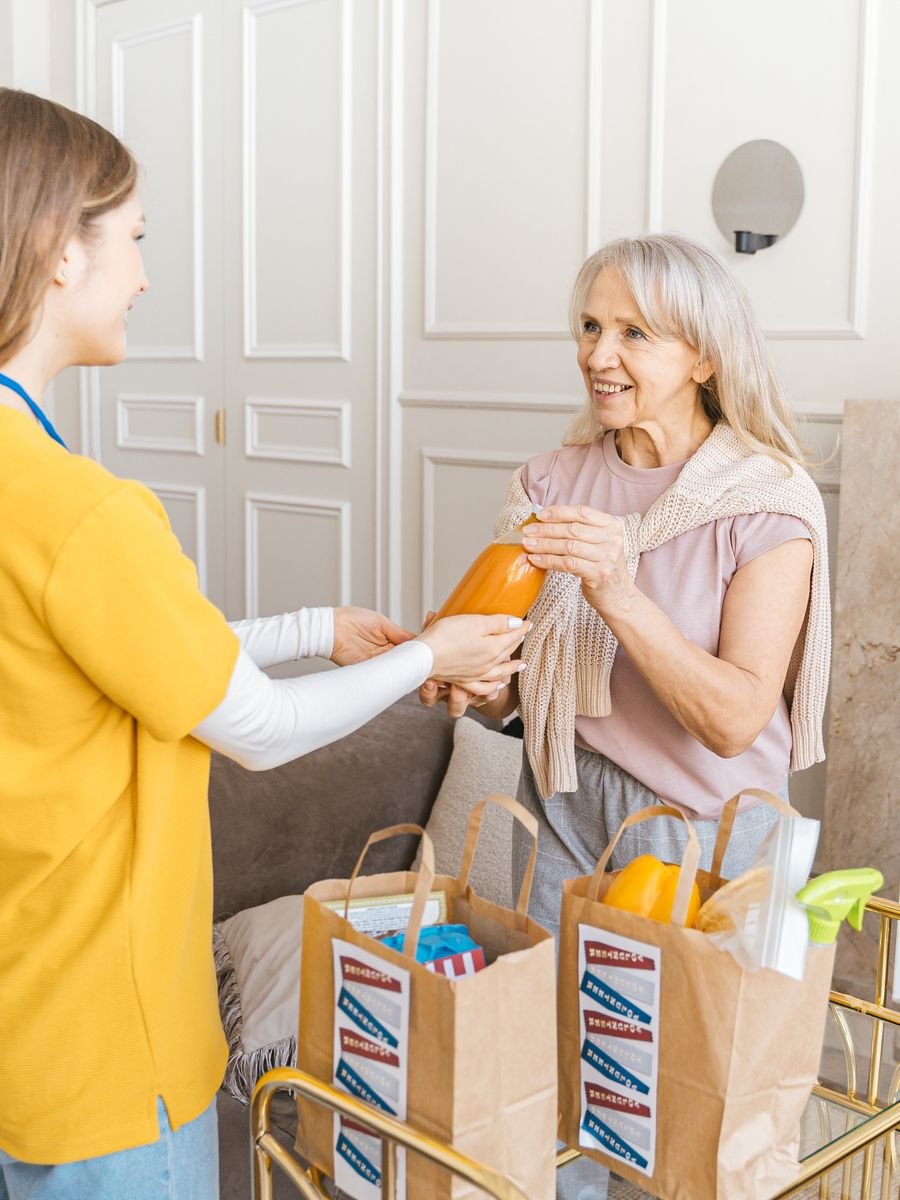 A caregiver bringing groceries and supplies to a client at her home