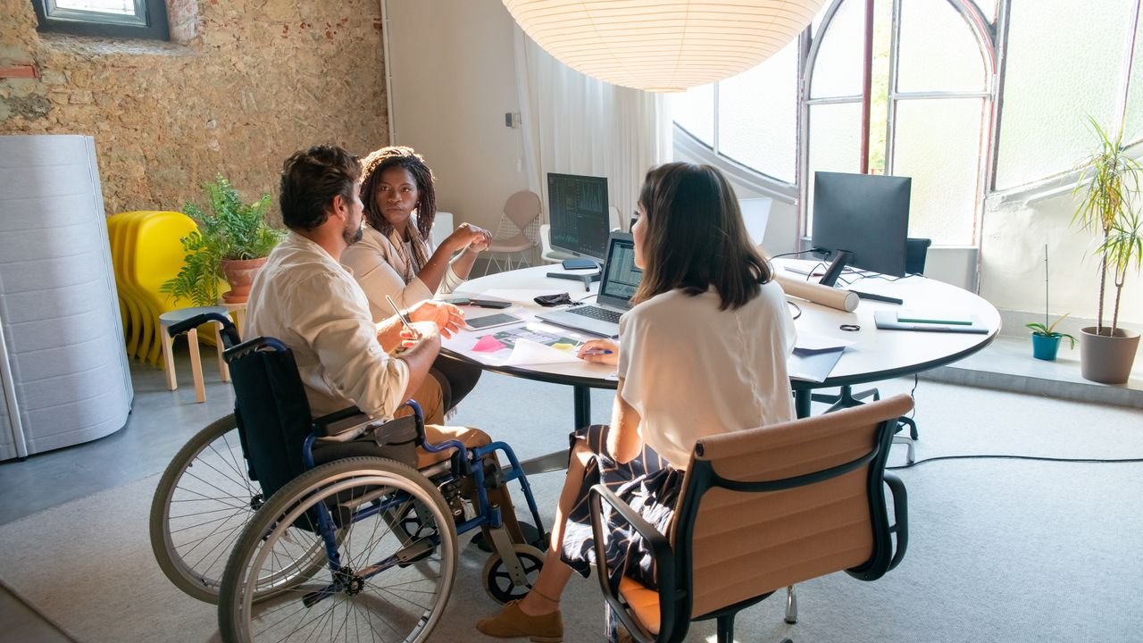 A wheelchair user contributing to a team meeting in an accessible workplace